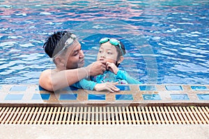 Happy asian father take care his daughter  in swimming pool