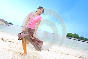 Happy Asian female dancing on beach