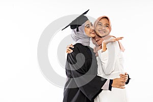 Happy asian female graduate student wearing toga hugging her friend