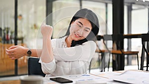 Happy asian female office worker relaxing at work and stretching her arms