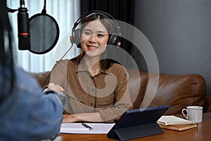 Happy Asian female radio host greeting her special guest, shaking hands, welcoming her guest