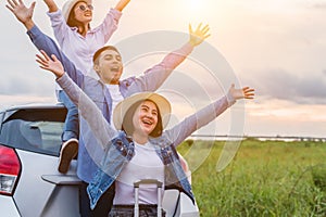 Happy Asian friends spread arms widely and breathed fresh air with happiness mood in on raod trip in car trunk. People lifestyle