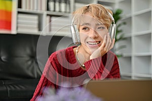 A happy Asian gay man is daydreaming while enjoying the music in his living room