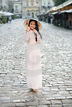 Happy asian girl dressed in traditional Ao Dai white dress with vietnamese conical hat Non La, Leaf Hat.