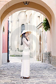 Happy asian girl dressed in traditional Ao Dai white dress with vietnamese conical hat Non La, Leaf Hat.