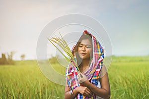 Happy Asian girl enjoy in green rice field, countryside of Thailand at sunset