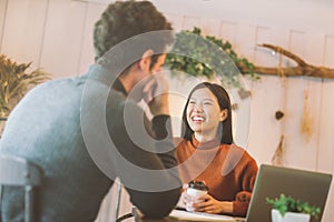 Happy Asian girl and friends chatting and using laptop in cafe at the coffee shop cafe in university talking and laughing together