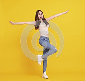 Happy Asian girl jumping and celebrating  isolated over yellow