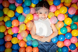 Happy asian girl playing in colorful balls pool