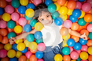 Happy asian girl playing in colorful balls pool