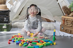 Happy Asian girl playing with colorful blocks