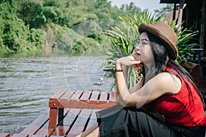 Happy Asian girl red shirt and brown hat on the river in nature background