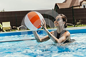 happy asian girl in swimsuit and sunglasses playing with beach ball