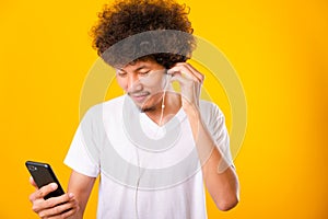 Happy asian handsome man with curly hair he smiling enjoying listening to music on earphones using a mobile smartphone