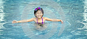 Happy asian kid big smile to playing swim in water pool at summer