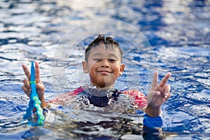 Happy asian kid boy swiming on swiming pool in the summer