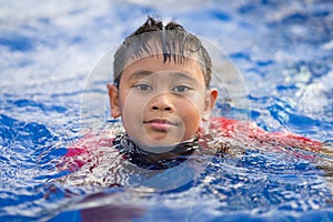 Happy asian kid boy swiming on swiming pool in the summer