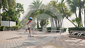 Happy Asian kid preschool ride scooter or kick board on road in park outdoors on summer day