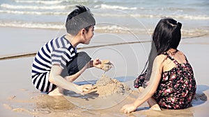 Happy asian kids playing sand on beach