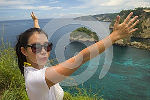 Happy Asian Korean woman in sunglasses enjoying amazing coast scene from view point at tropical paradise beach with diamond rock