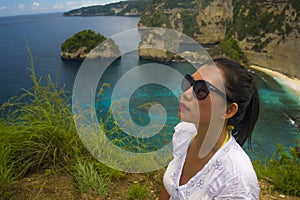 Happy Asian Korean woman in sunglasses enjoying amazing coast scene from view point at tropical paradise beach with diamond rock