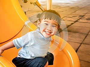 Happy Asian little child girl having fun on slide at playground