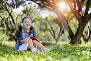 Happy asian little child girl reading book in the garden