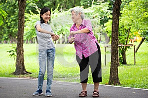 Happy asian little child girl smiling and exercise with elderly woman in outdoor park,granddaughter,senior grandmother dancing,