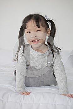 Happy Asian little cute girl lying on bed and smile