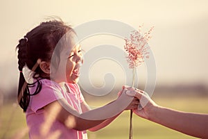 Happy asian little girl giving grass flower to her mother