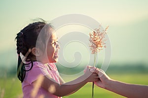 Happy asian little girl giving grass flower to her mother