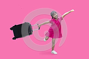 Happy Asian little girl hold a baggage wearing pink mini dress in summer isolated on pink  background.