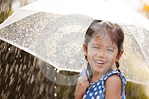 Happy asian little girl with umbrella in rain