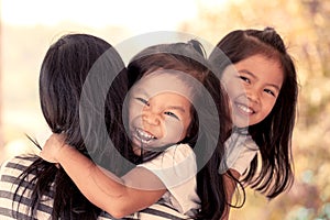 Happy asian little girls hugging mother