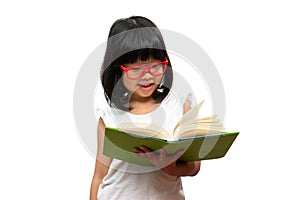 Happy Asian little preschool girl wearing red glasses holding and read a green book on white isolated background. Concept of