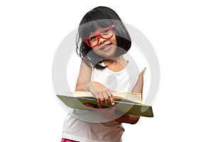 Happy Asian little preschool girl wearing red glasses holding and read a green book on white isolated background. Concept of