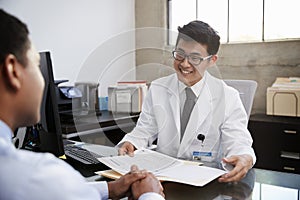 Happy Asian male doctor in consultation with male patient