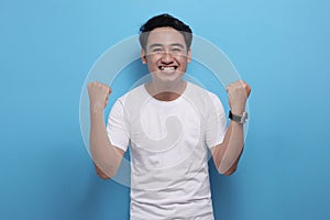 Happy Asian man shows winning gesture, celebrating victory