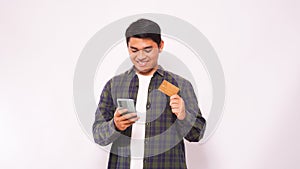 Happy Asian man smiling while holding blank credit card and mobile phone