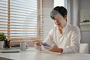 Happy Asian man using mobile banking application to transfer money or pay online bills