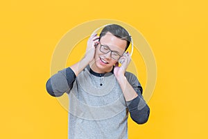 Happy Asian man wearing headphones listening to relaxing music
