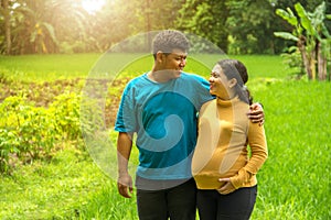 Happy Asian maternity couple looking at each other, over tropical farm land