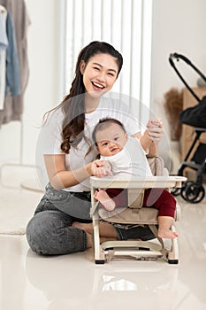 Happy asian mom playing and spending time with her newborn baby and looking at camera together at home.Adorable baby boy smile