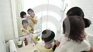 happy asian mother and daughter brush their teeth together