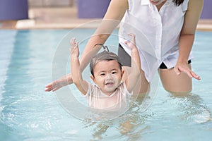 A Happy Asian mother and daughter are enjoy swimming in pool , lifestyle, parenthood, family concept