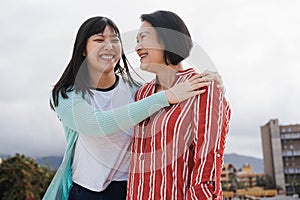 Happy asian mother and daughter having fun hugging outdoor - Focus on senior woman face