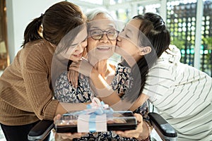 Happy asian mother,daughter meeting old grandparent,giving grandmother a gift,hugging,female elderly hold  present box,woman,child