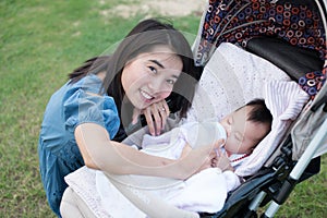 Happy asian mother feeding to baby on the stroller