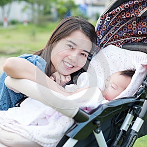 Happy asian mother feeding to baby on the stroller