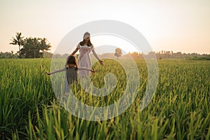 Happy asian mother and kid walking in rice field